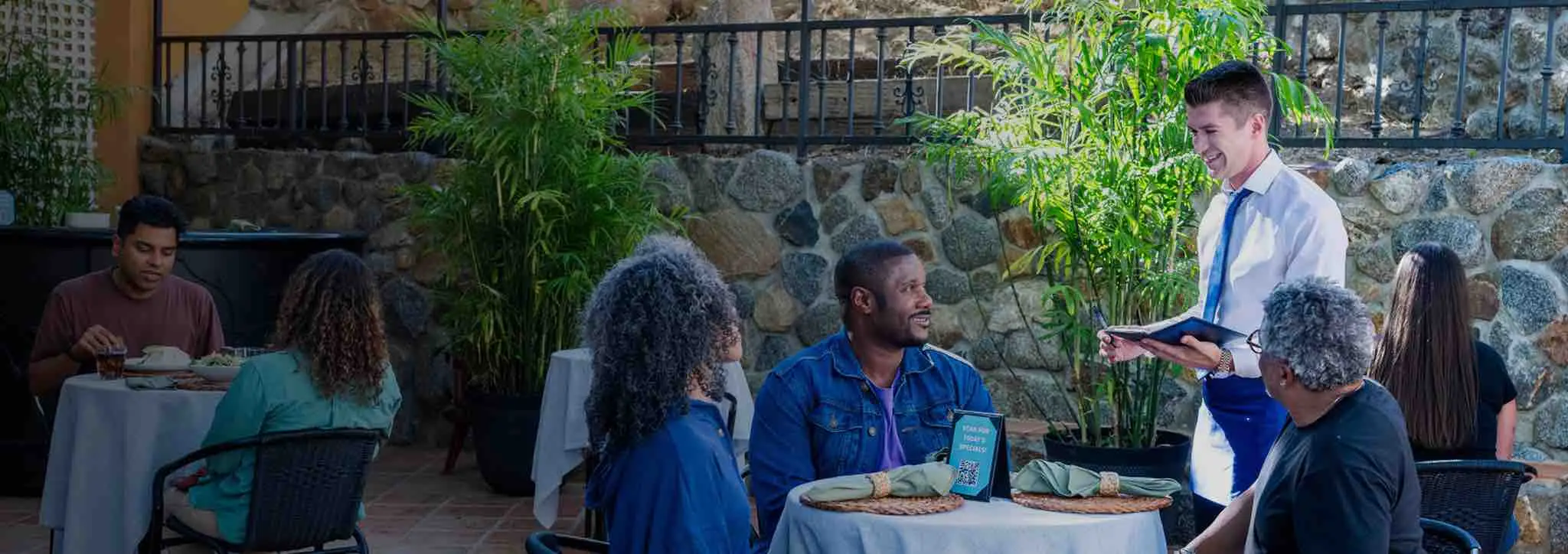 A family sitting at a restaurant ordering from a waiter