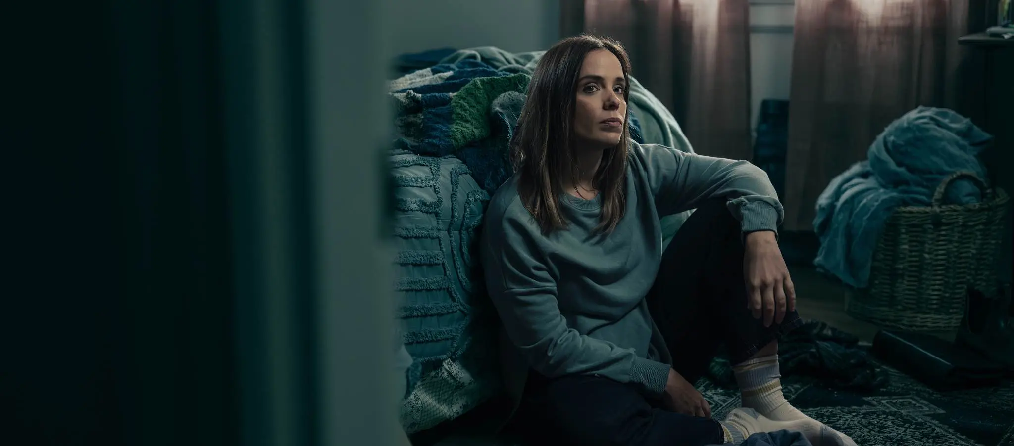Person sitting on bedroom floor.